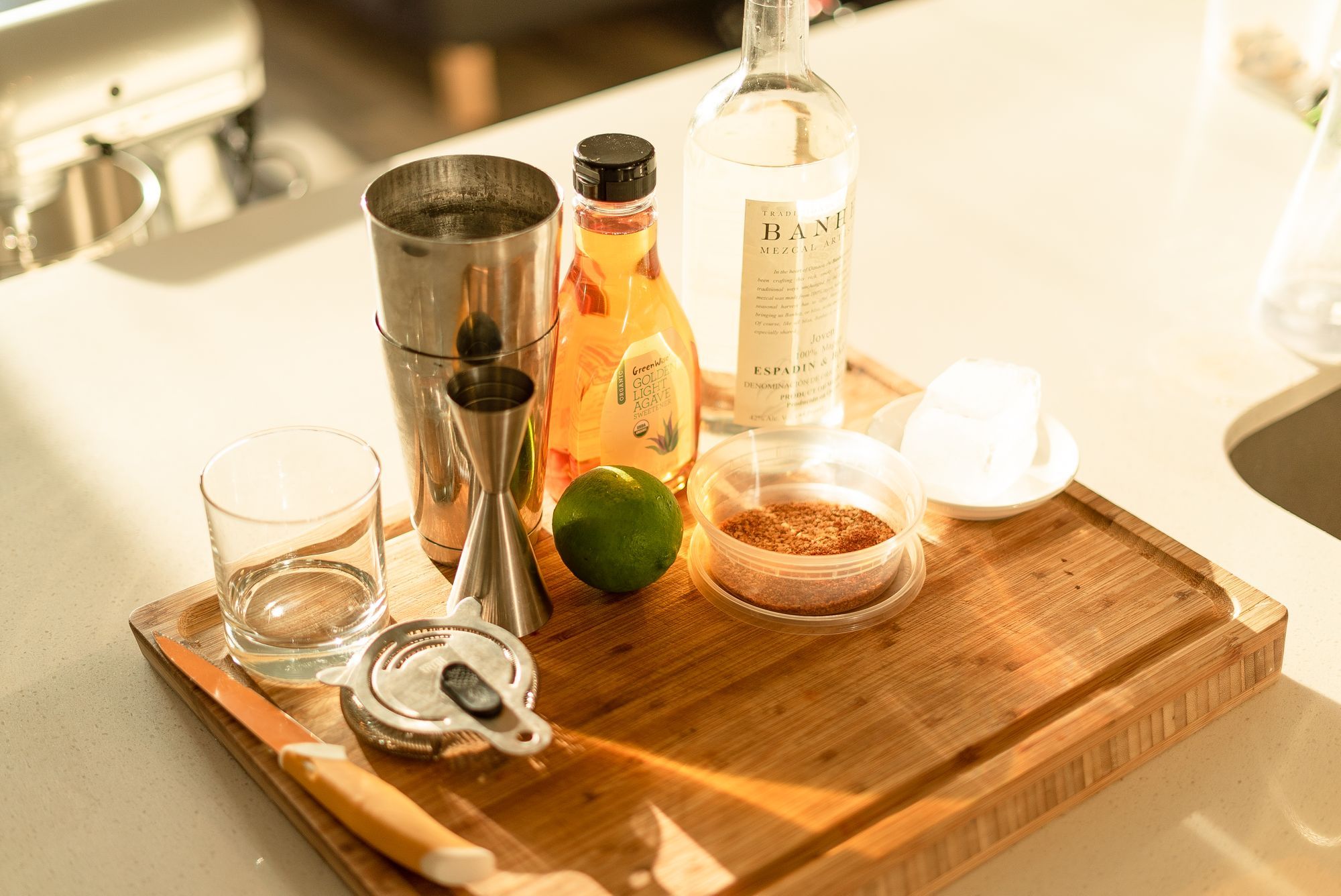 ingredients for making a mezcal margarita over a thick cutting board
